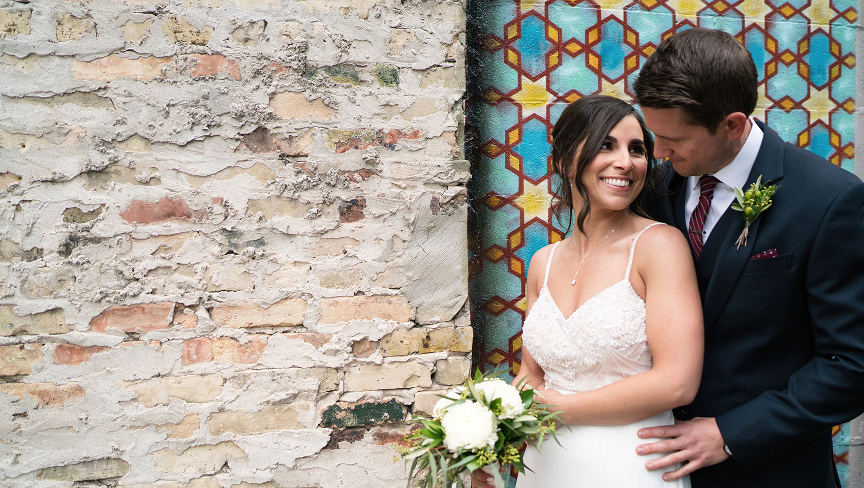 Newlyweds posing in front of wall